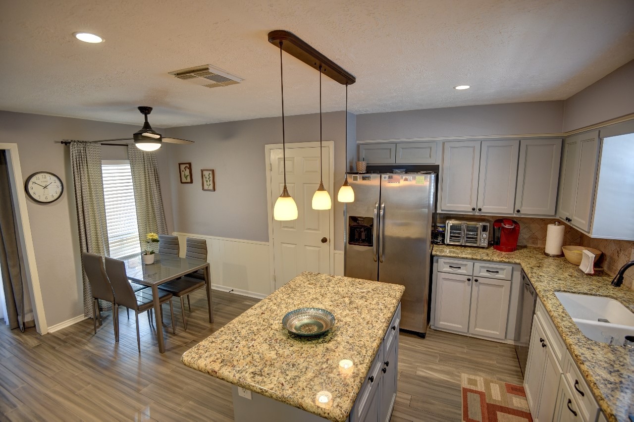 25810 Fairbrook Lane Spring, TX 77373 - Photo 14 of 33 This modern kitchen features a central island with granite countertops, stainless steel appliances, and ample cabinetry. It has recessed lighting, a ceiling fan, and a cozy dining area, creating a comfortable and functional space