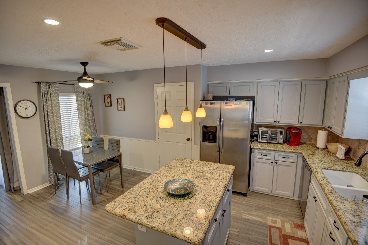 25810 Fairbrook Lane Spring, TX 77373 - Photo 15 of 33 This modern kitchen features a central island with granite countertops, stainless steel appliances, and ample cabinetry. It has recessed lighting, a ceiling fan, and a cozy dining area, creating a comfortable and functional space