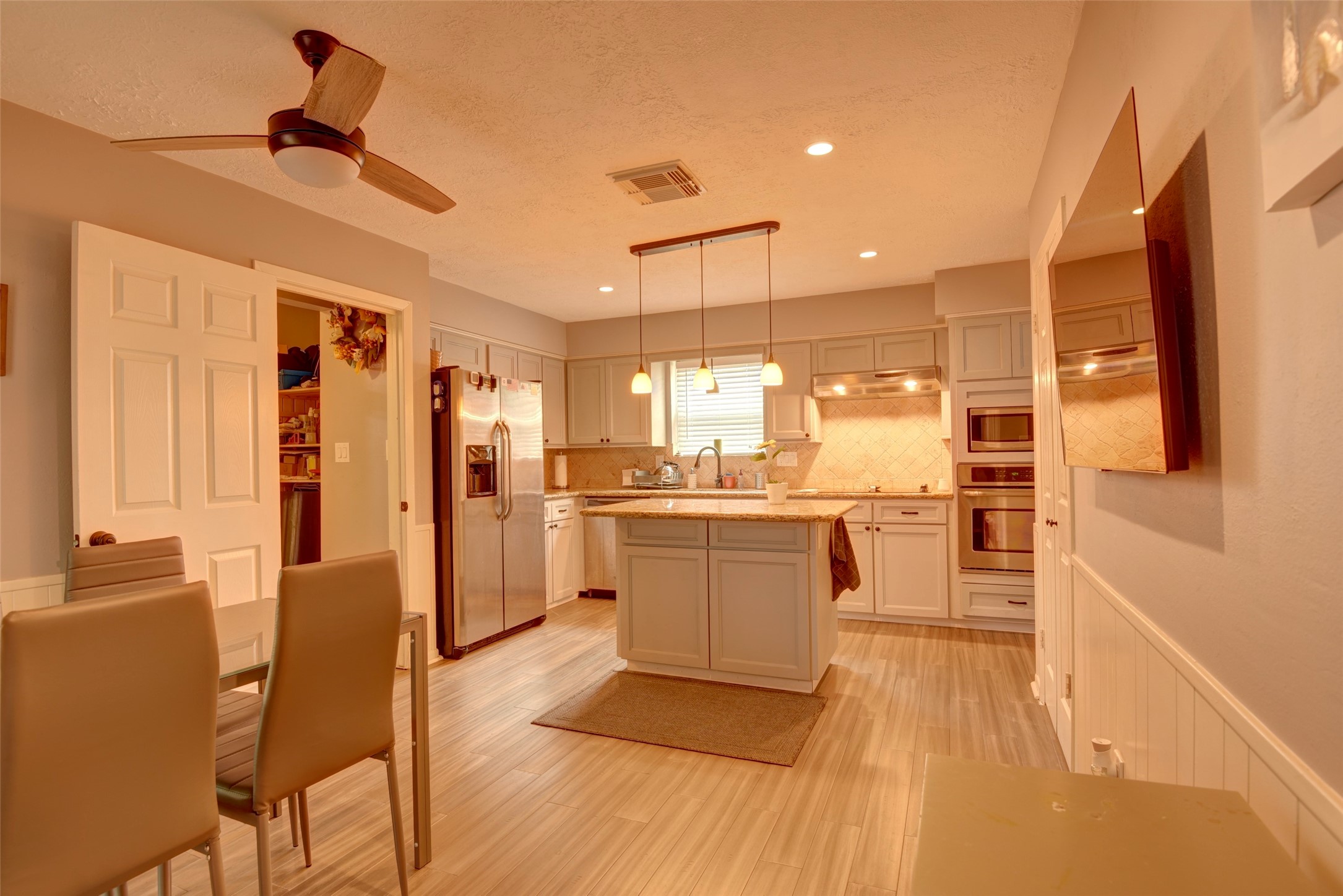 25810 Fairbrook Lane Spring, TX 77373 - Photo 16 of 33 This modern kitchen features a central island with granite countertops, stainless steel appliances, and ample cabinetry. It has recessed lighting, a ceiling fan, and a cozy dining area, creating a comfortable and functional space