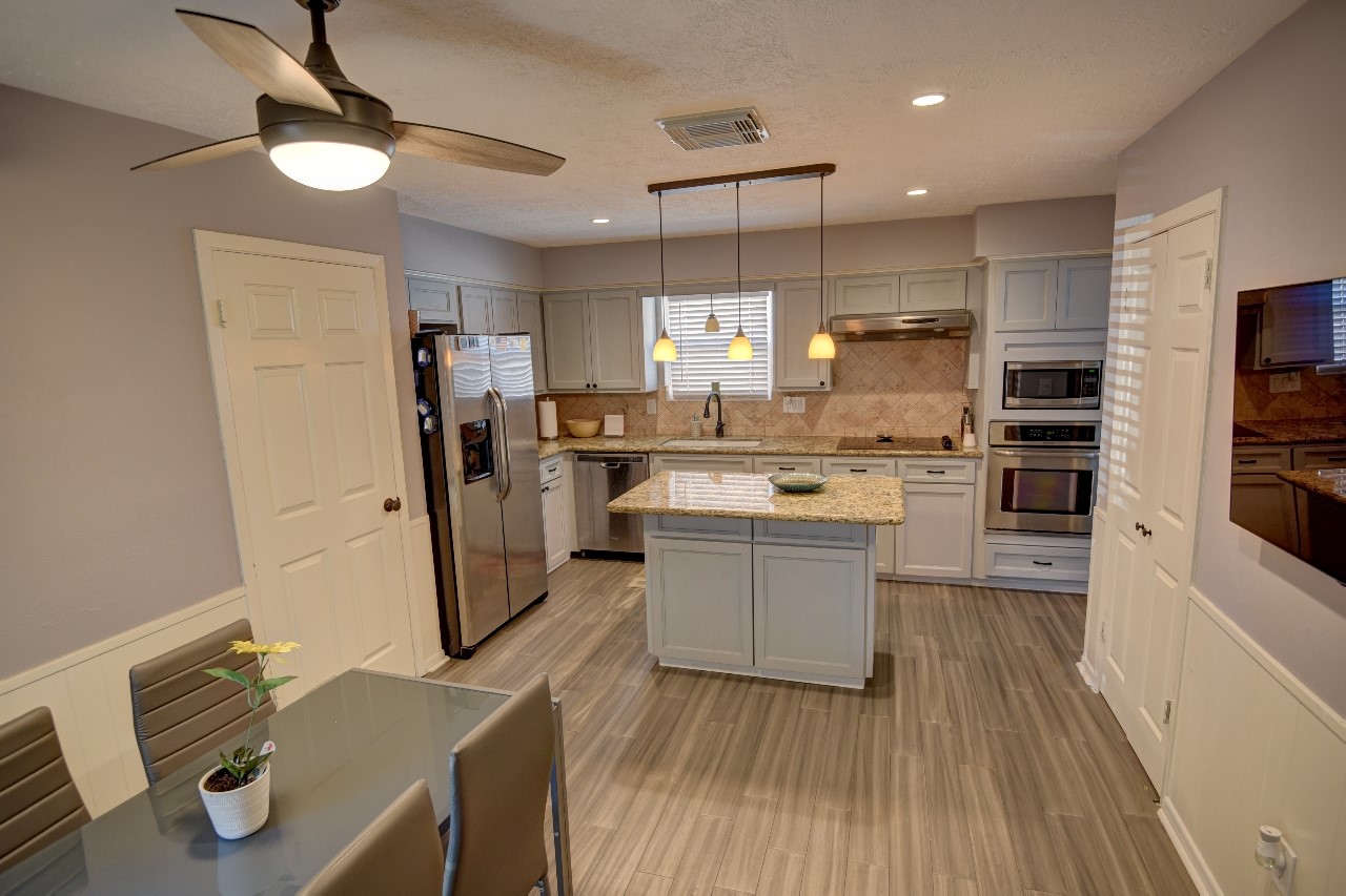 25810 Fairbrook Lane Spring, TX 77373 - Photo 17 of 33 This modern kitchen features a central island with granite countertops, stainless steel appliances, and ample cabinetry. It has recessed lighting, a ceiling fan, and a cozy dining area, creating a comfortable and functional space