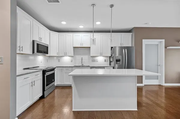 a kitchen with kitchen island white cabinets and stainless steel appliances