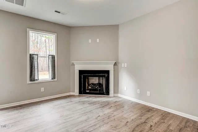 an empty room with a window and fireplace