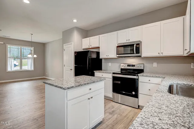 a kitchen with stainless steel appliances granite countertop a stove a sink and a microwave