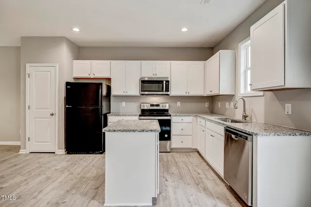 a kitchen with a refrigerator a stove top oven and cabinets