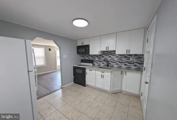 a kitchen with granite countertop a refrigerator and white cabinets