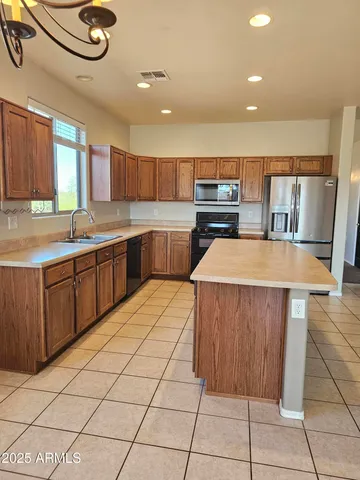 an empty room with chandelier fan and windows