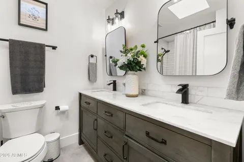 a bathroom with a granite countertop toilet sink and mirror