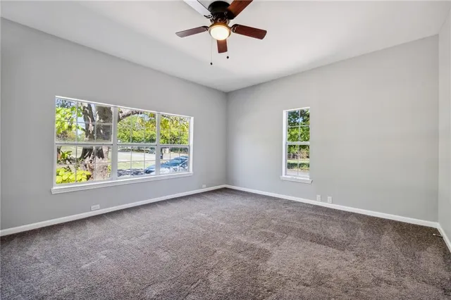 an empty room with windows and ceiling fan