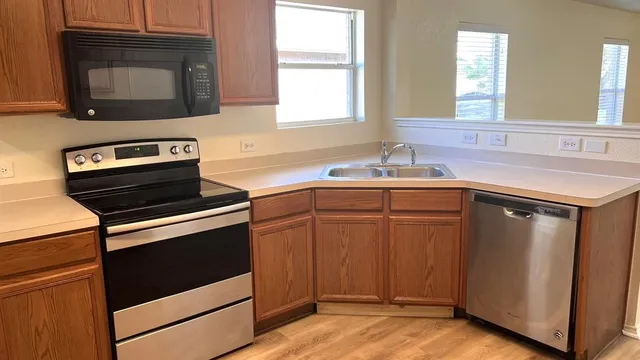 a kitchen with granite countertop a stove top oven a sink dishwasher and a microwave oven with wooden floor