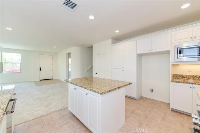 a hall with kitchen island granite countertop a sink and dishwasher stove