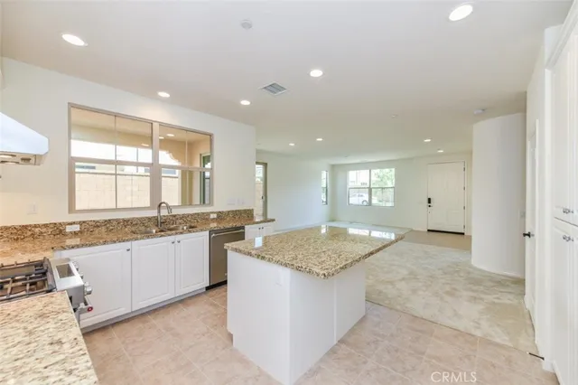 a large kitchen with granite countertop a sink a stove counter space and cabinets