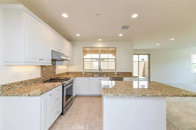 a large kitchen with granite countertop a sink a counter top space and stainless steel appliances