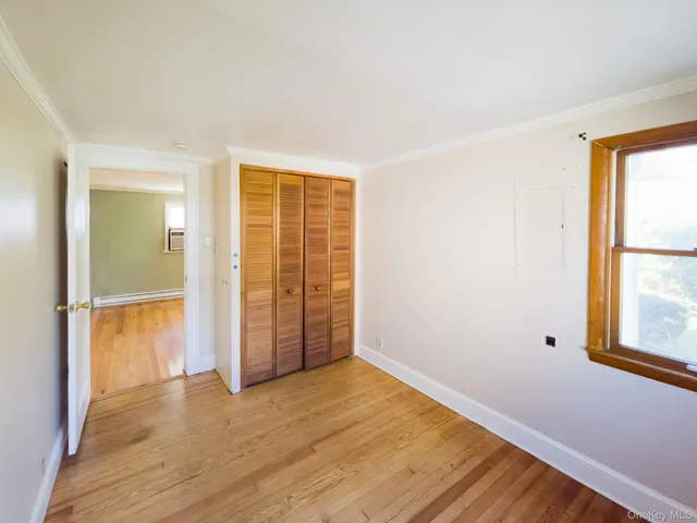 an empty room with wooden floor closet and windows