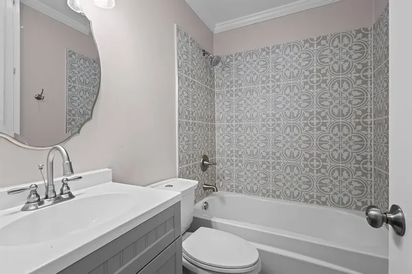 a bathroom with a granite countertop bathtub sink vanity mirror and toilet