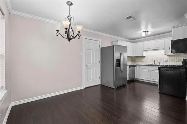 a kitchen with stainless steel appliances granite countertop white cabinets a refrigerator a sink a stove a microwave and wooden floor
