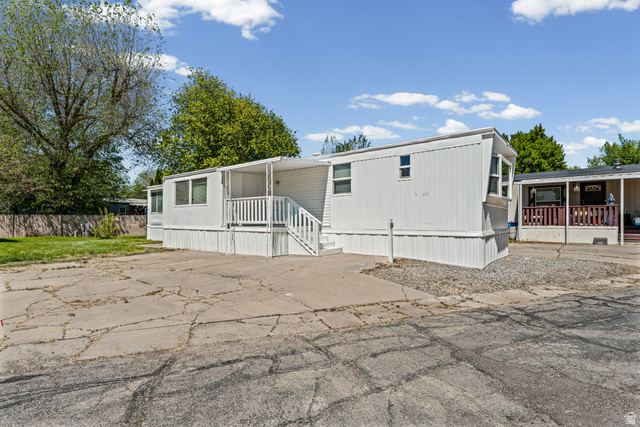 24 Grover Street Layton, UT 84041 - Photo 2 of 21 White manufactured home with a covered front porch, white exterior siding, and a skirted foundation