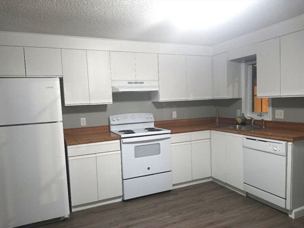 1821 Middlesex Street, Unit 10 Lowell, MA 01851 - Photo 2 of 6 a kitchen with white cabinets and white appliances