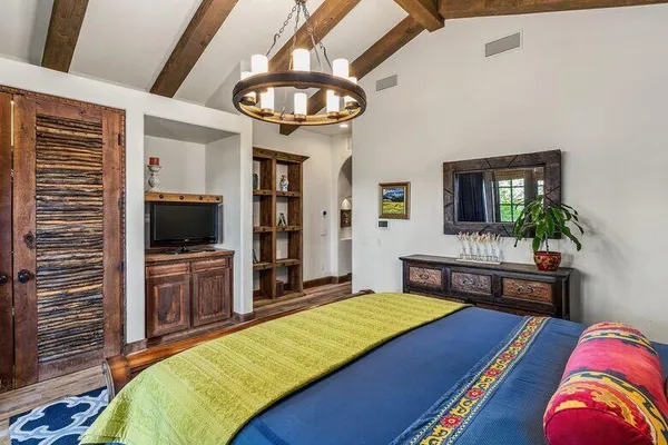 a bed sitting in a bedroom next to a lamp with a chandelier