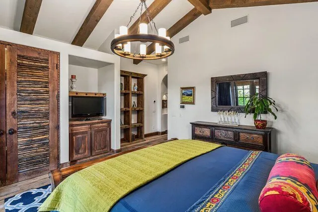 a bed sitting in a bedroom next to a lamp with a chandelier