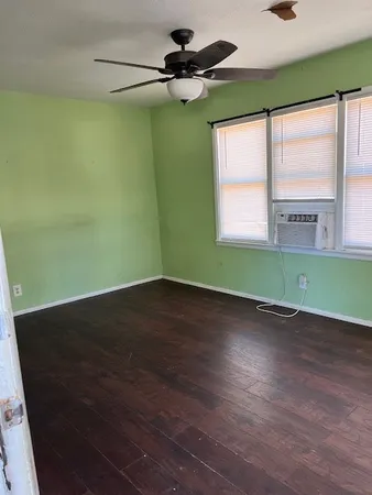 a view of an empty room with a window and wooden floor