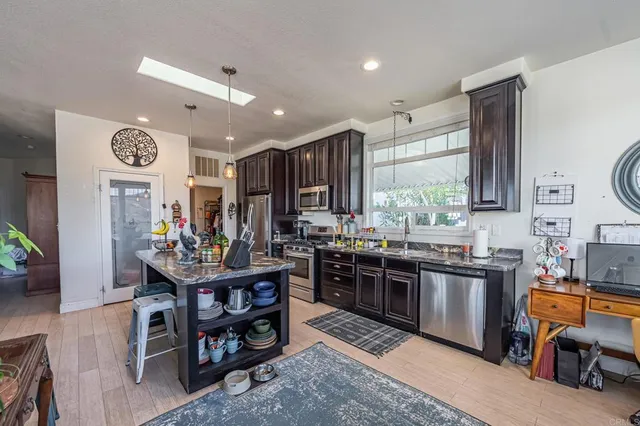 a kitchen with stainless steel appliances granite countertop sink stove top oven and cabinets
