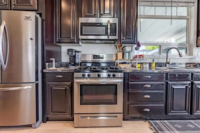 a kitchen with stainless steel appliances granite countertop a stove a refrigerator and a sink