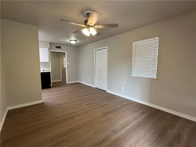 a view of an empty room with wooden floor and a window