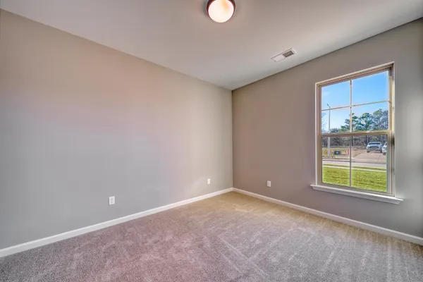 a view of an empty room with window and bathroom