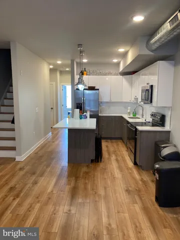 a kitchen with stainless steel appliances granite countertop a sink dishwasher a stove and a refrigerator with wooden floor