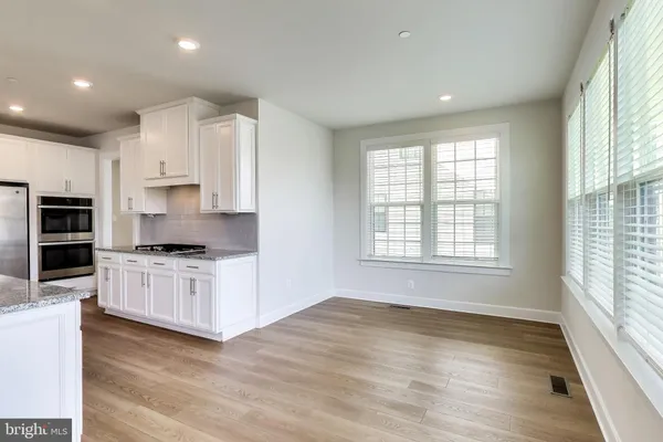 a kitchen with stainless steel appliances granite countertop a stove a sink and white cabinets