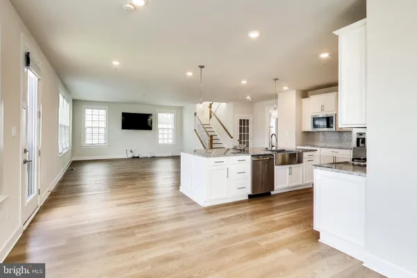 a view of kitchen with microwave a stove and white cabinets