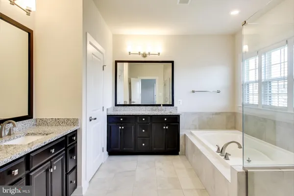 a bathroom with a bathtub double vanity sink and mirror