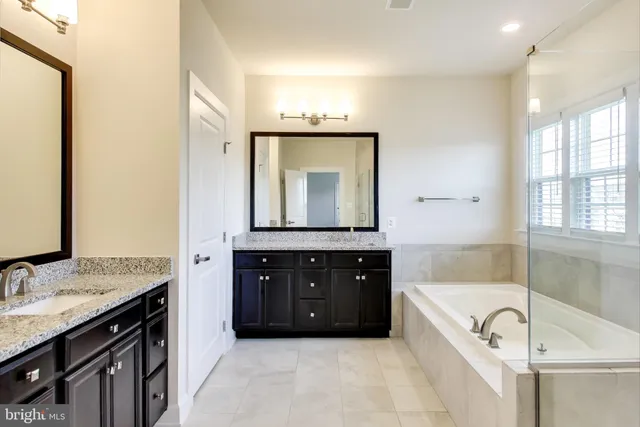 a bathroom with a bathtub double vanity sink and mirror