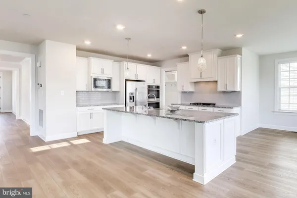 a kitchen with kitchen island granite countertop a sink a stove a refrigerator and white cabinets