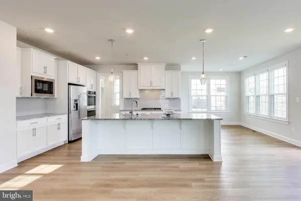 a large kitchen with cabinets wooden floor and stainless steel appliances