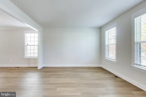 an empty room with wooden floor and windows with curtains