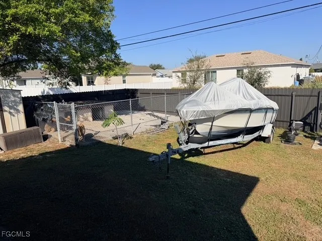 a view of a patio with table and chairs under an umbrella with a barbeque grill and a small yard