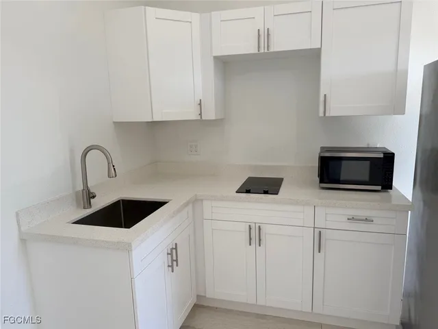a kitchen with white cabinets a sink and a stove with wooden floor