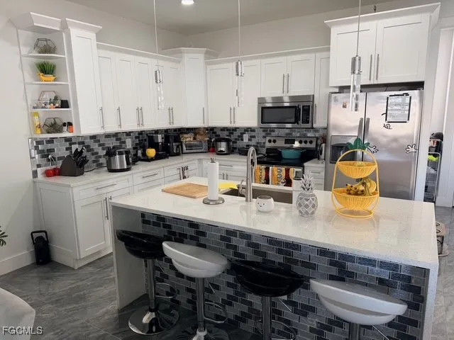 a kitchen with stainless steel appliances granite countertop a table chairs stove and cabinets