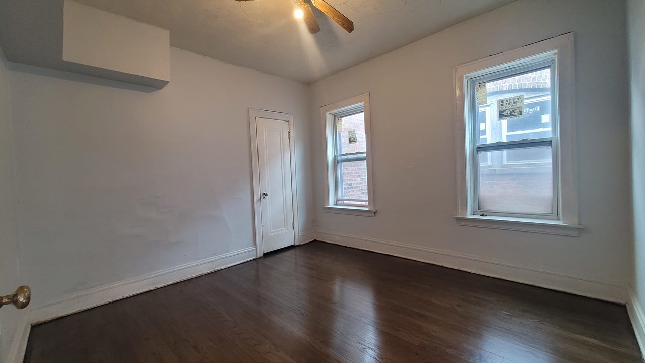 7842 South Bennett Avenue, Unit 2 Chicago, IL 60649 - Photo 3 of 7 an empty room with wooden floor and windows