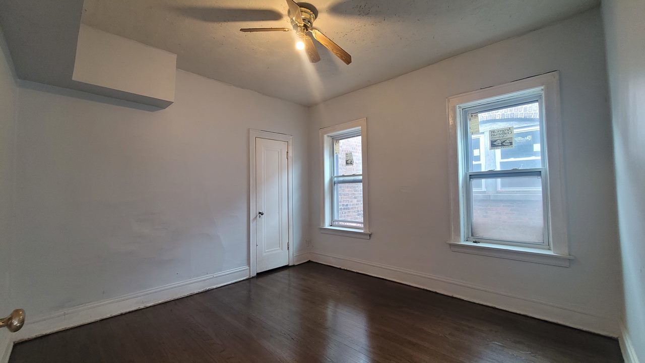 7842 South Bennett Avenue, Unit 2 Chicago, IL 60649 - Photo 4 of 7 a view of an empty room with wooden floor and a window