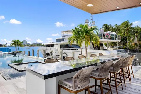 a view of a kitchen with kitchen island a stove a chimney a sink and a dining table with garden view