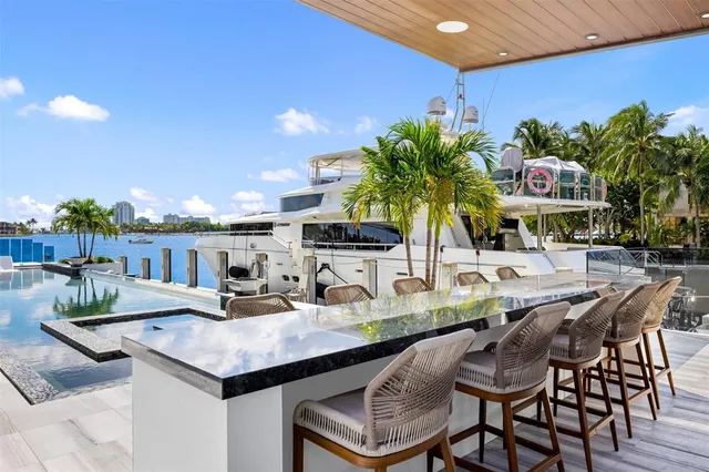 a view of a kitchen with kitchen island a stove a chimney a sink and a dining table with garden view