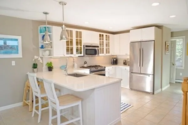 a kitchen with stainless steel appliances granite countertop a refrigerator a stove a sink dishwasher a dining table and chairs with wooden floor
