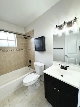 a bathroom with a sink a toilet a mirror and bathtub