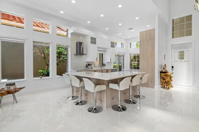 a large white kitchen with stainless steel appliances kitchen island granite countertop a refrigerator and a stove