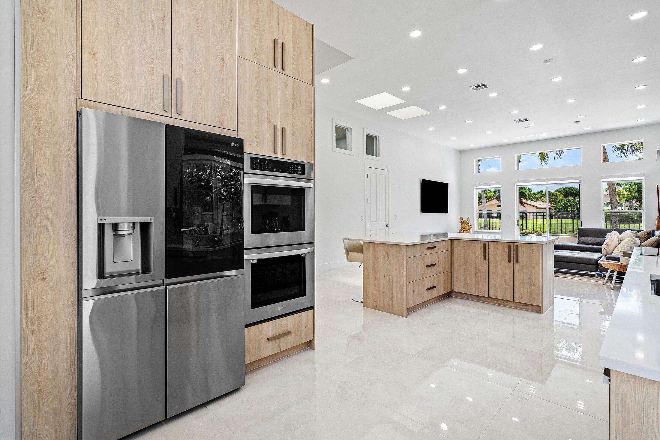 6334 Northwest 24th Street Boca Raton, FL 33434 - Photo 15 of 56 a large white kitchen with stainless steel appliances kitchen island granite countertop a refrigerator and a stove