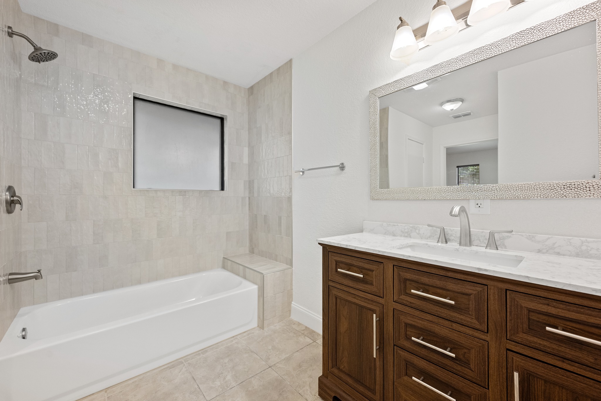 7210 Smokey Hill Road Austin, TX 78736 - Photo 18 of 29 A well-appointed bathroom offers a sleek vanity with a wide mirror and a combined tub and shower area.