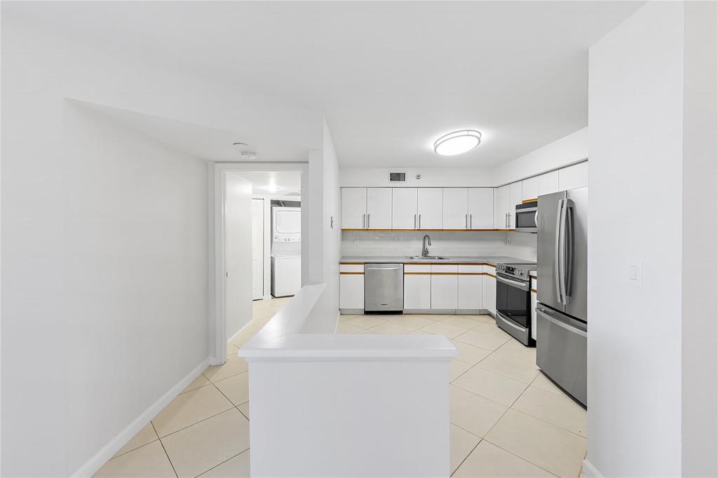 3530 Mystic Pointe Drive, Unit 2707 Aventura, FL 33180 - Photo 8 of 11 a kitchen with white cabinets and stainless steel appliances