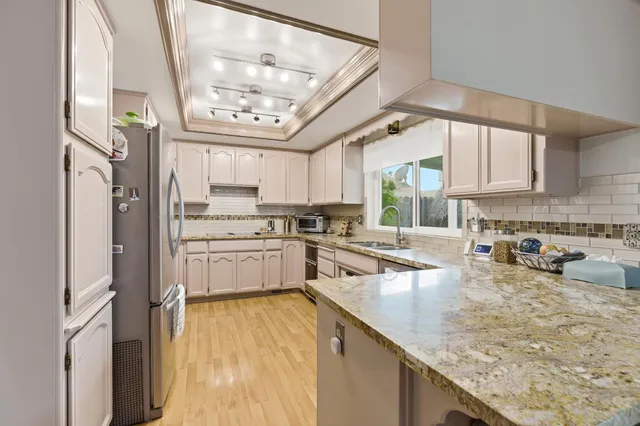 a kitchen with stainless steel appliances granite countertop a sink window and cabinets